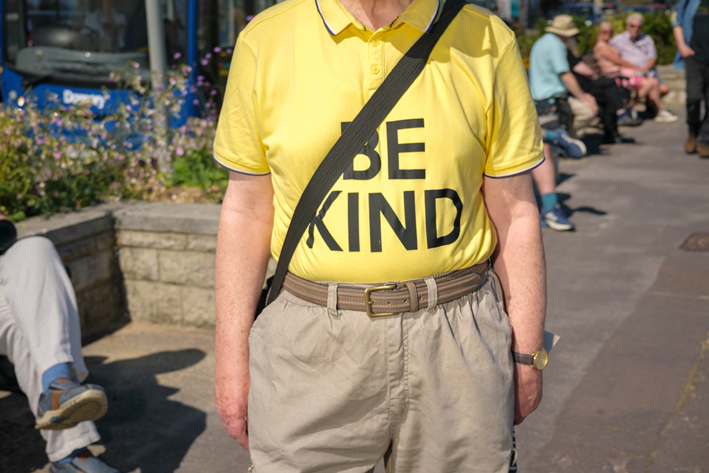 persons torso wearing yellow be kind shirt
