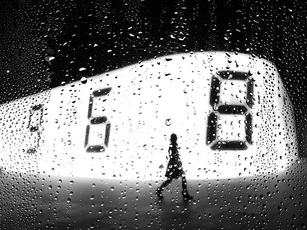 looking through rainy window at person walking past lit up screen with 968 digits smartphone street photography