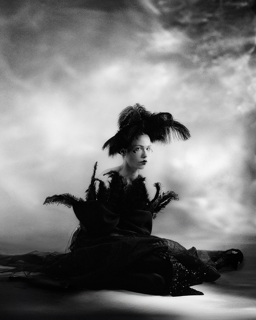 woman poses for portrait in feather head piece and feather dress