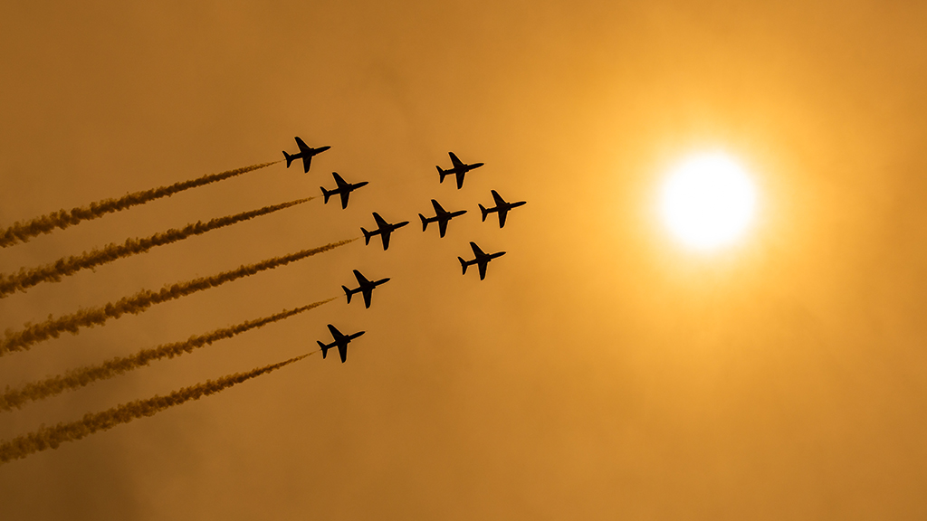 red arrows formation silhouette against orange sky