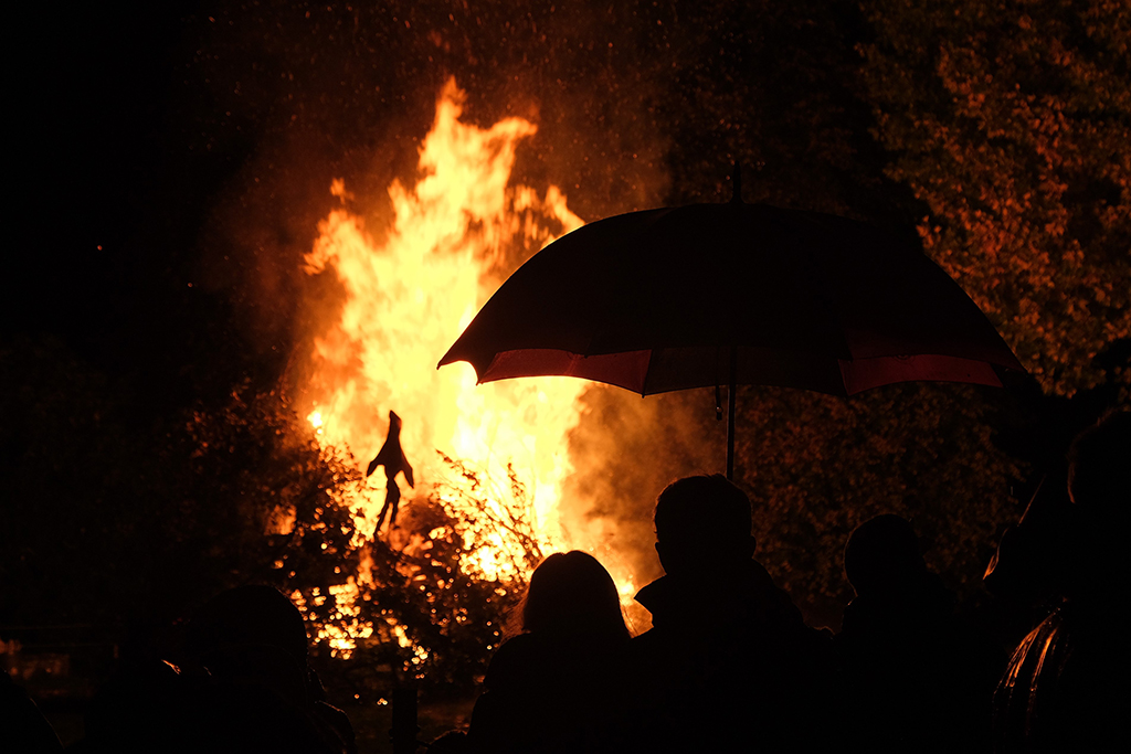 silhouette of two people under an umbrella at a bonfire