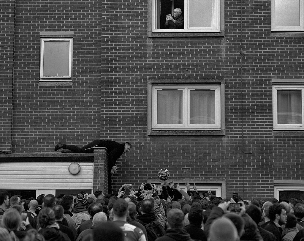 street photo of a football being thrown over a crowd