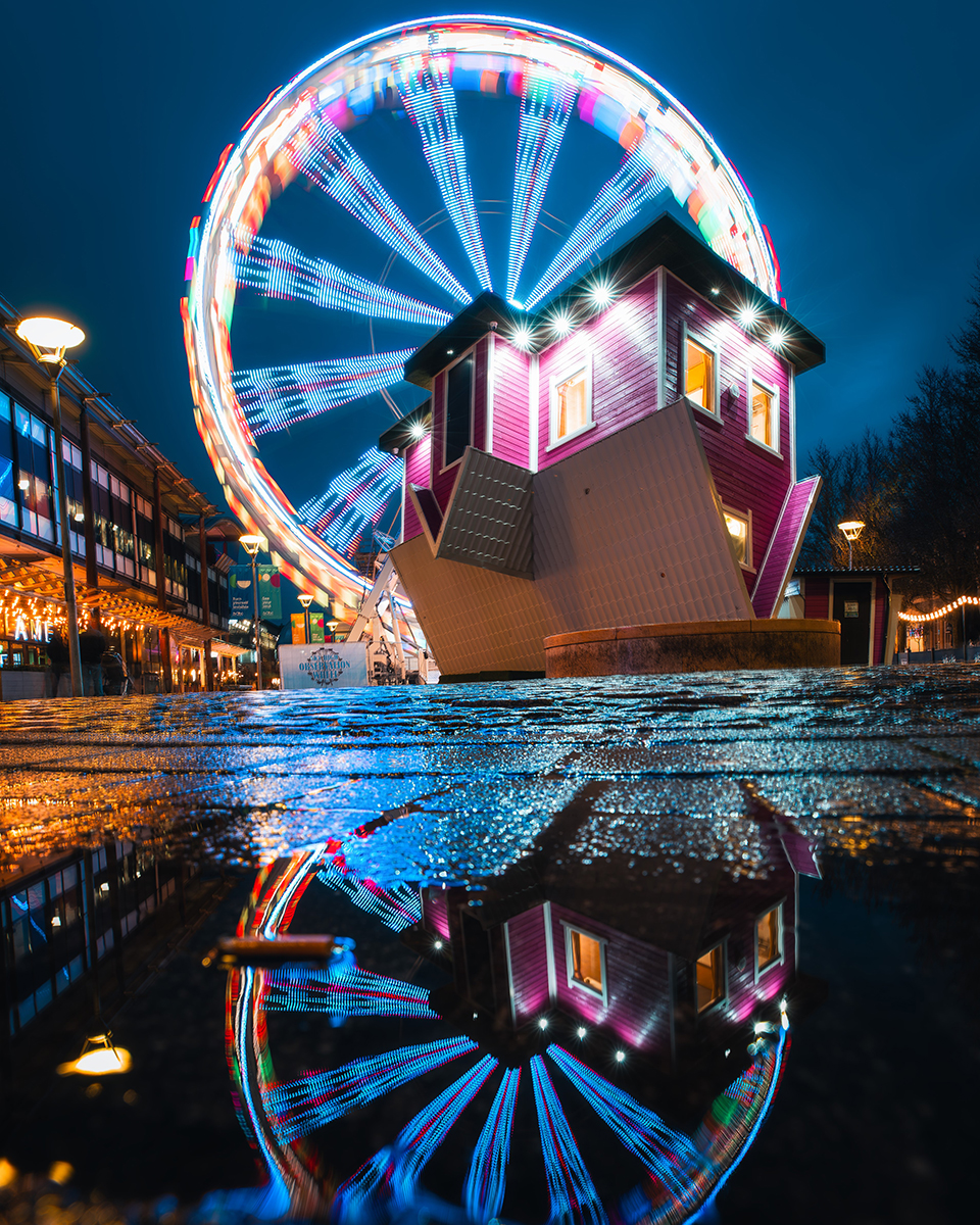 upside down house at night with ferris wheel behind