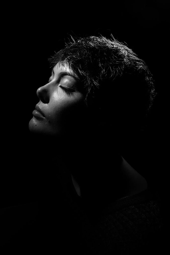 black and white portrait of a woman in shadows with eyes shut