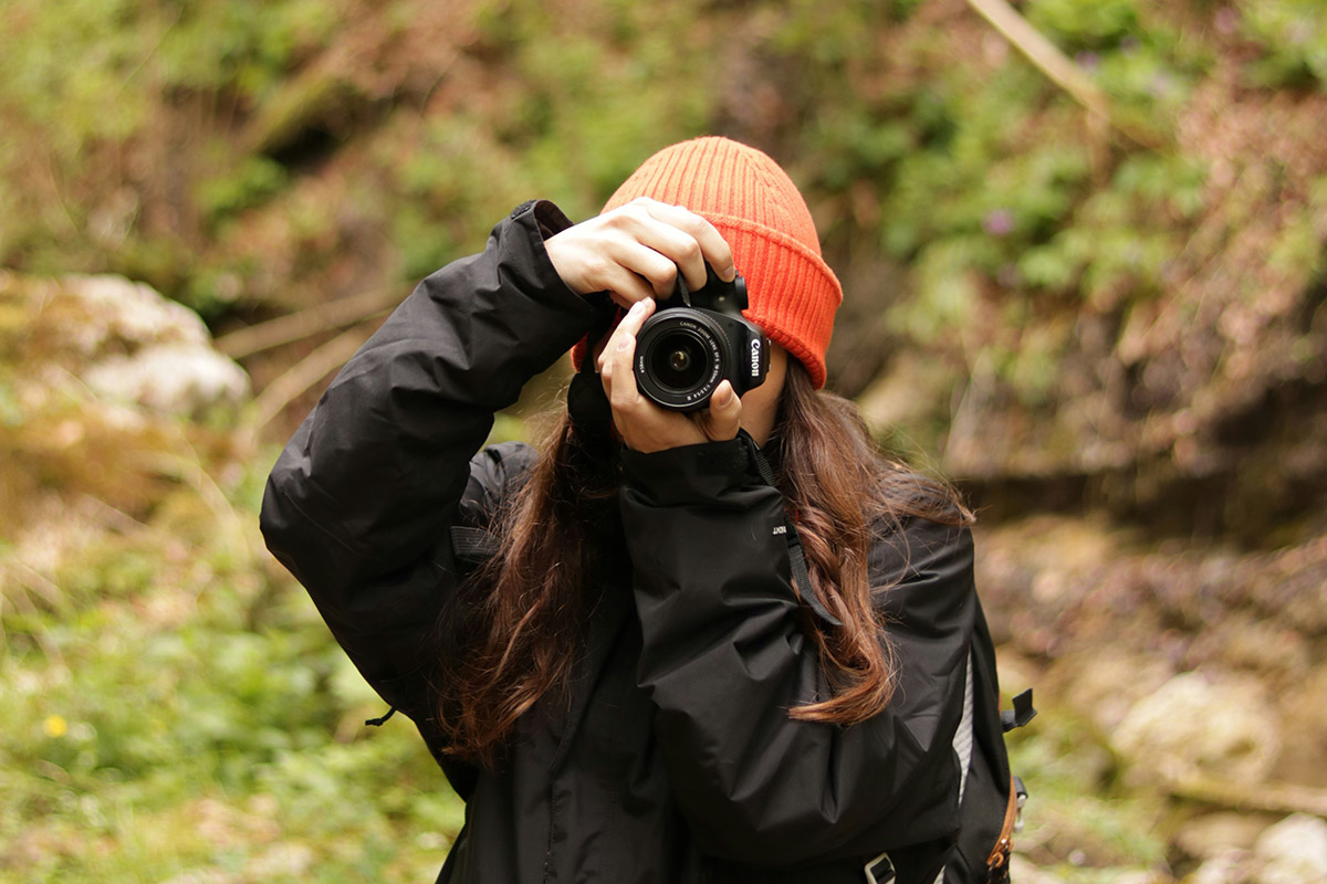 woman in an orange beanie taking a photo with a camera
